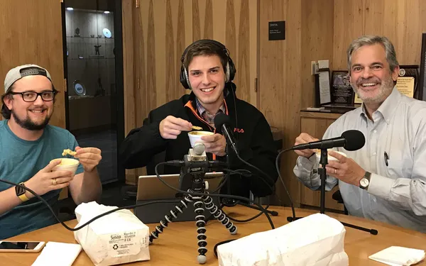 Daulton Venglar, Bryce Seifert, and Austin Mayor Steve Adler hold up queso and chips in front of podcasting equipment