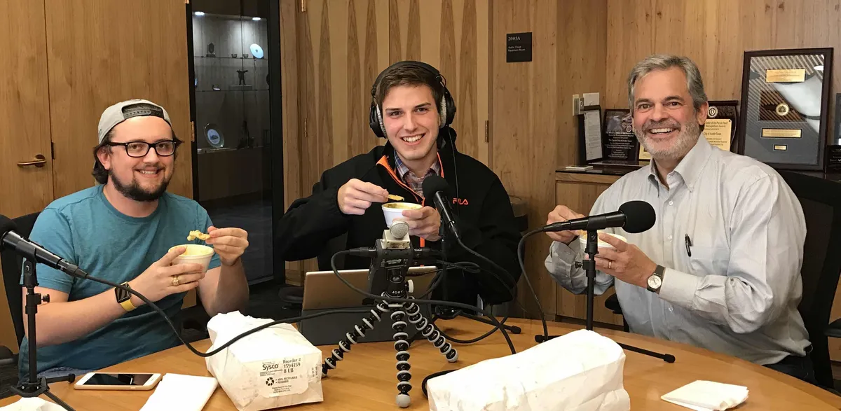 Daulton Venglar, Bryce Seifert, and Austin Mayor Steve Adler hold up queso and chips in front of podcasting equipment.